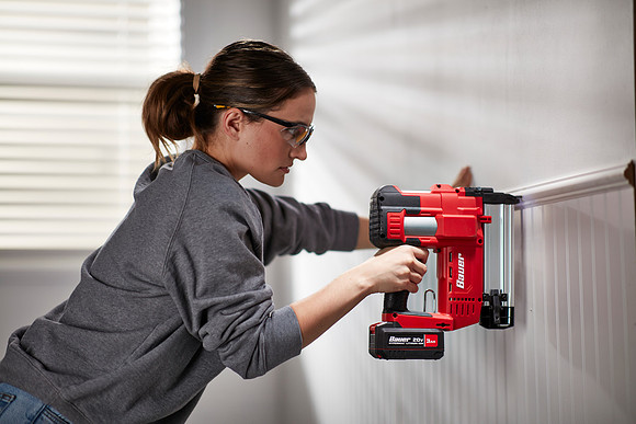 Woman installing chair rail with a w/power tool